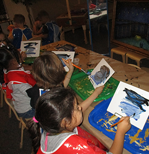 Four students in a classroom paint together